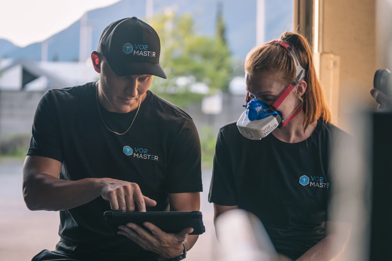 Coach reviewing live gas exchange data on a tablet beside a client wearing the VO2 Master mask